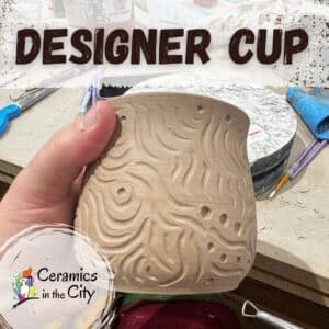 Hand-carved leather-hard stoneware cup with textured surface design in a pottery studio
